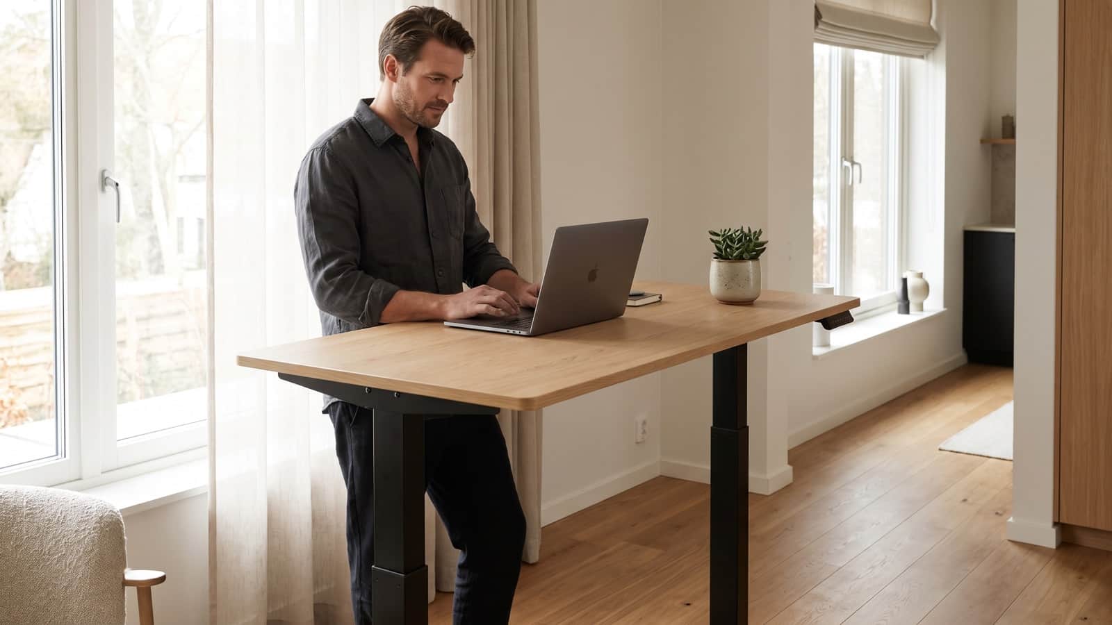 Person working while standing at a height-adjustable desk in a bright home office