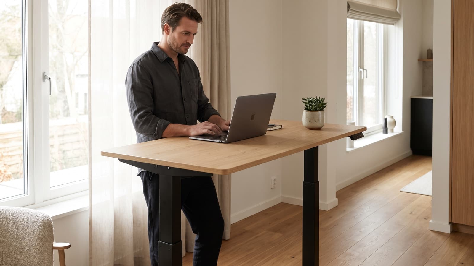 Person working while standing at a height-adjustable desk in a bright home office